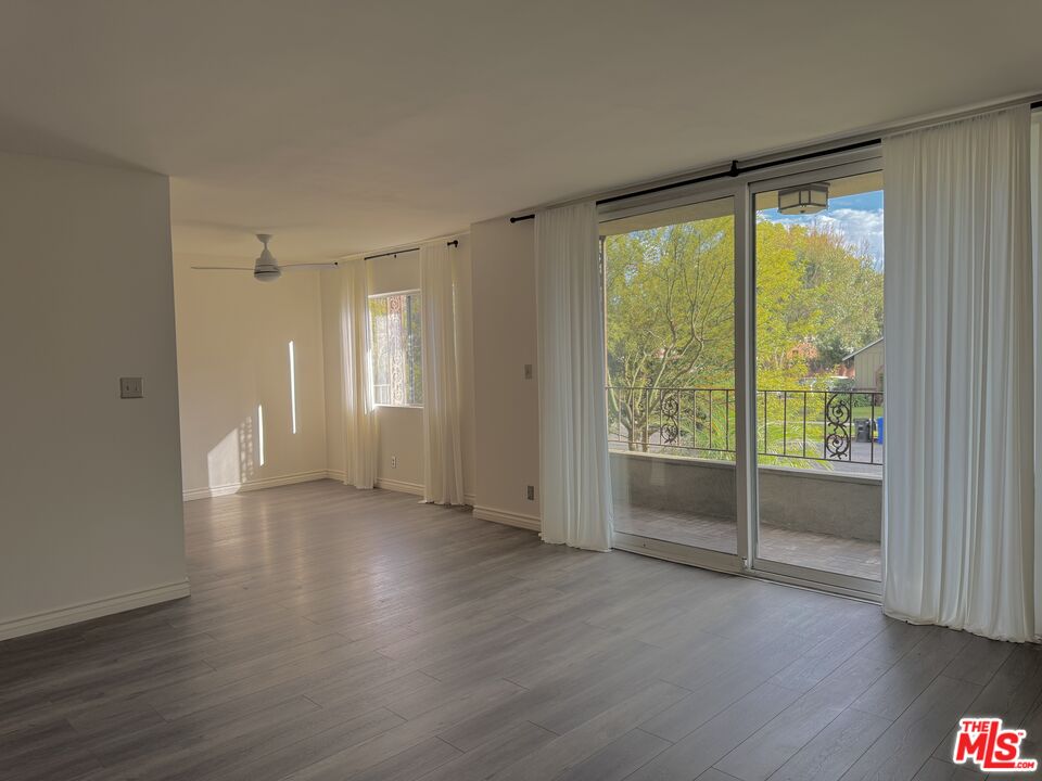 a view of an empty room with wooden floor and a window