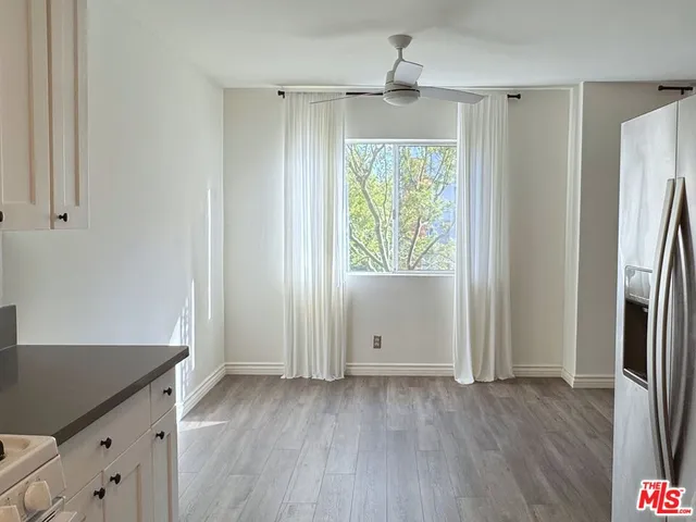 an empty room with wooden floor cabinet and windows