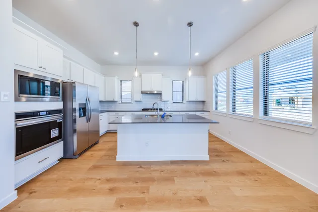 a kitchen with stainless steel appliances granite countertop a sink a stove a microwave a center island and cabinets