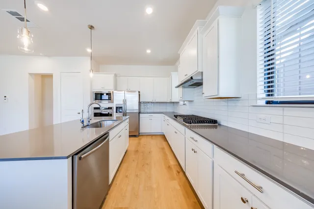 a kitchen with stainless steel appliances granite countertop a sink a stove and a refrigerator
