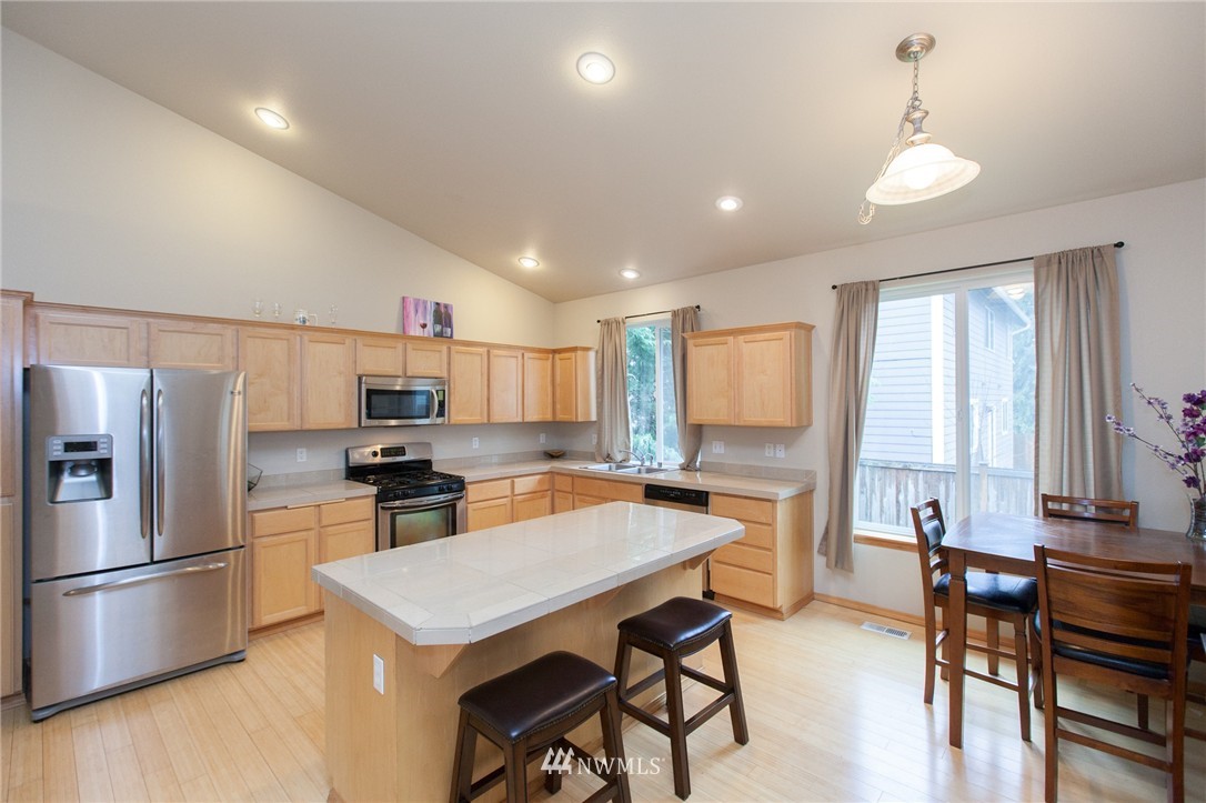 6745 Southeast 5th Street Renton, WA 98059 - Photo 2 of 25 a kitchen with a refrigerator a stove a dining table and chairs with wooden floor