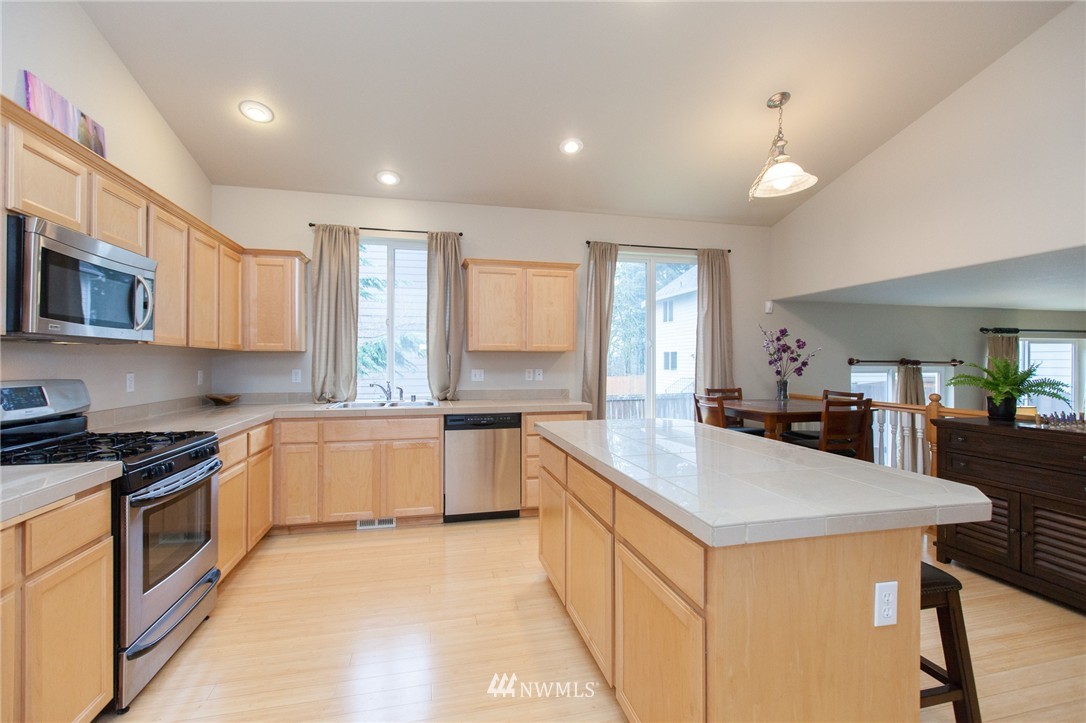 6745 Southeast 5th Street Renton, WA 98059 - Photo 3 of 25 a kitchen with granite countertop a sink a counter top space stainless steel appliances cabinets and a counter top space