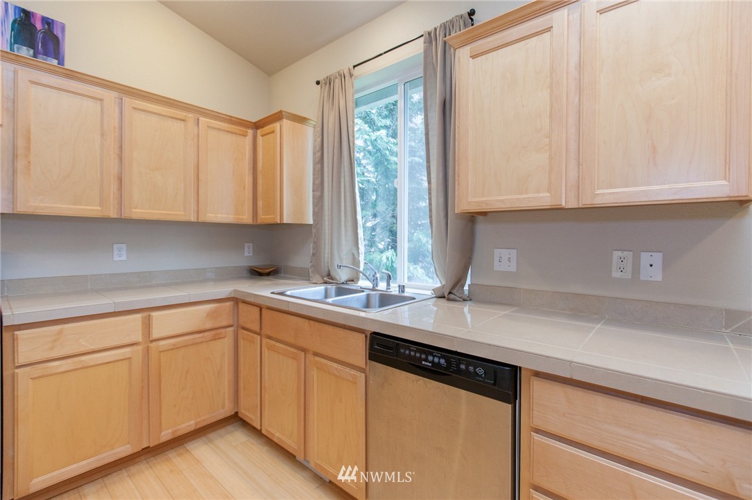 6745 Southeast 5th Street Renton, WA 98059 - Photo 4 of 25 a kitchen with stainless steel appliances granite countertop a sink a stove and white cabinets with wooden floor
