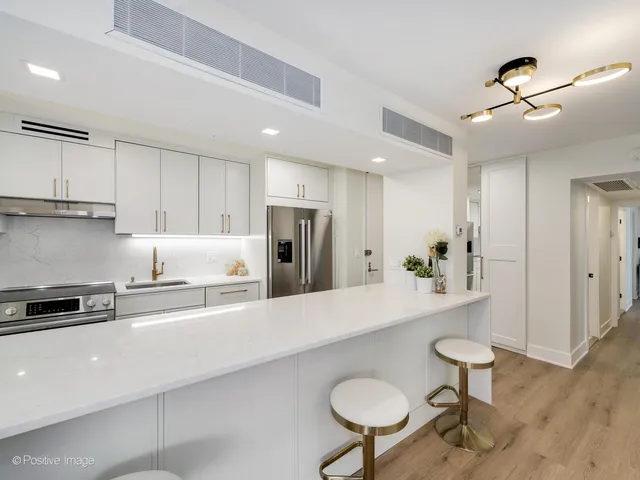 a kitchen with stainless steel appliances a sink a stove a refrigerator cabinets and living room view