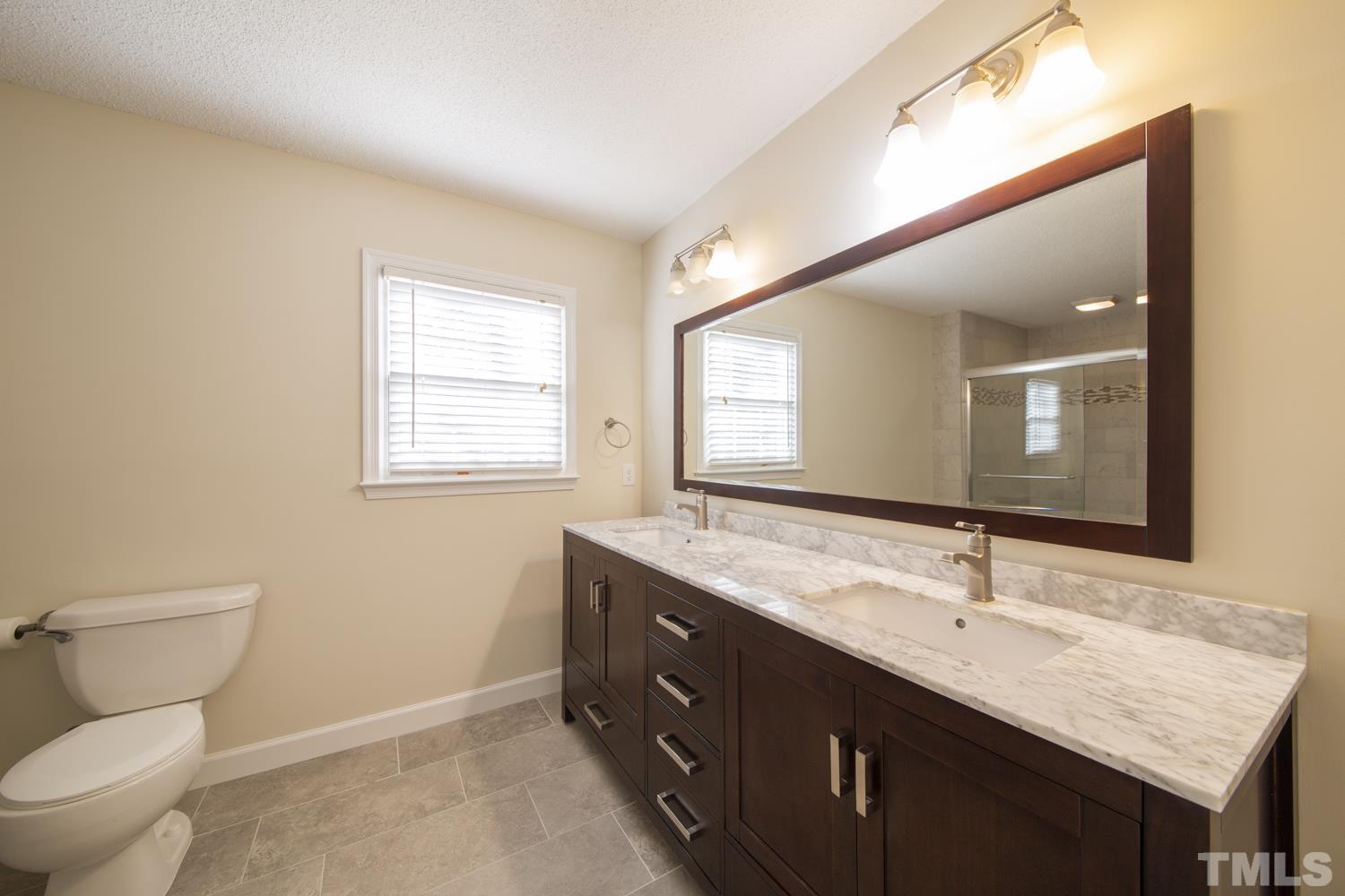 11805 North Exeter Way Raleigh, NC 27613 - Photo 16 of 19 a bathroom with a double vanity sink toilet and a mirror