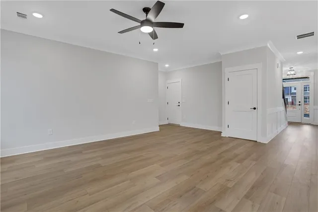 an empty room with wooden floor and a ceiling fan