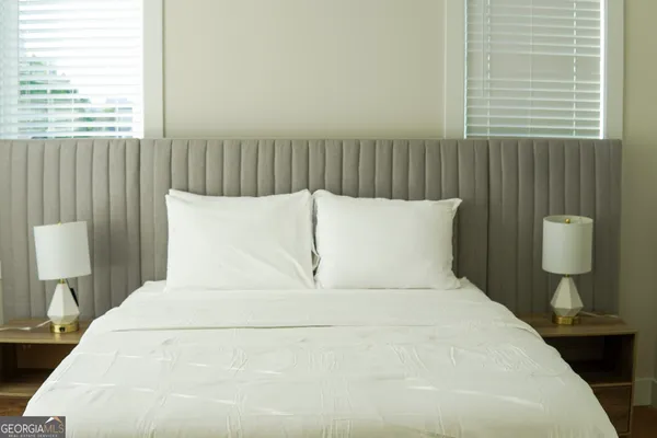 a large white bed in a bedroom next to a window
