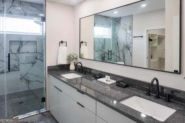 a bathroom with a granite countertop sink a mirror and shower