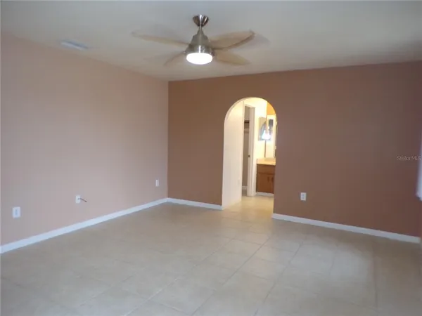 an empty room that has a window and a ceiling fan