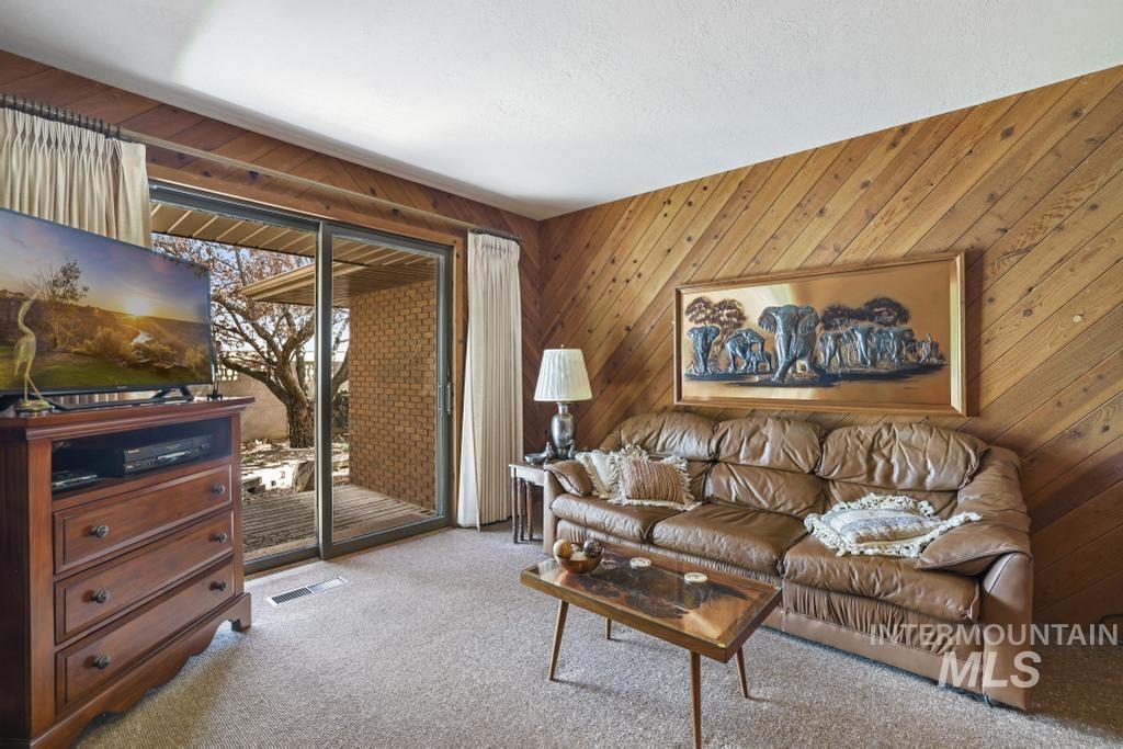 2018 Rancho Vista Drive Twin Falls, ID 83301 - Photo 36 of 50 Living area featuring diagonal wood-paneling, light-toned carpeting, and a sliding glass door providing access to an exterior brick patio