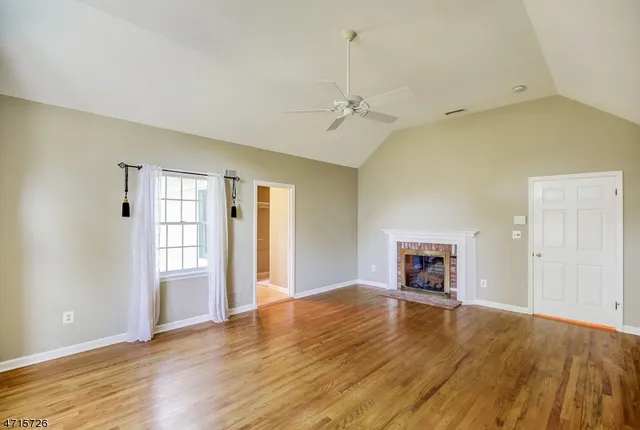 a view of empty room with a fireplace and wooden floor