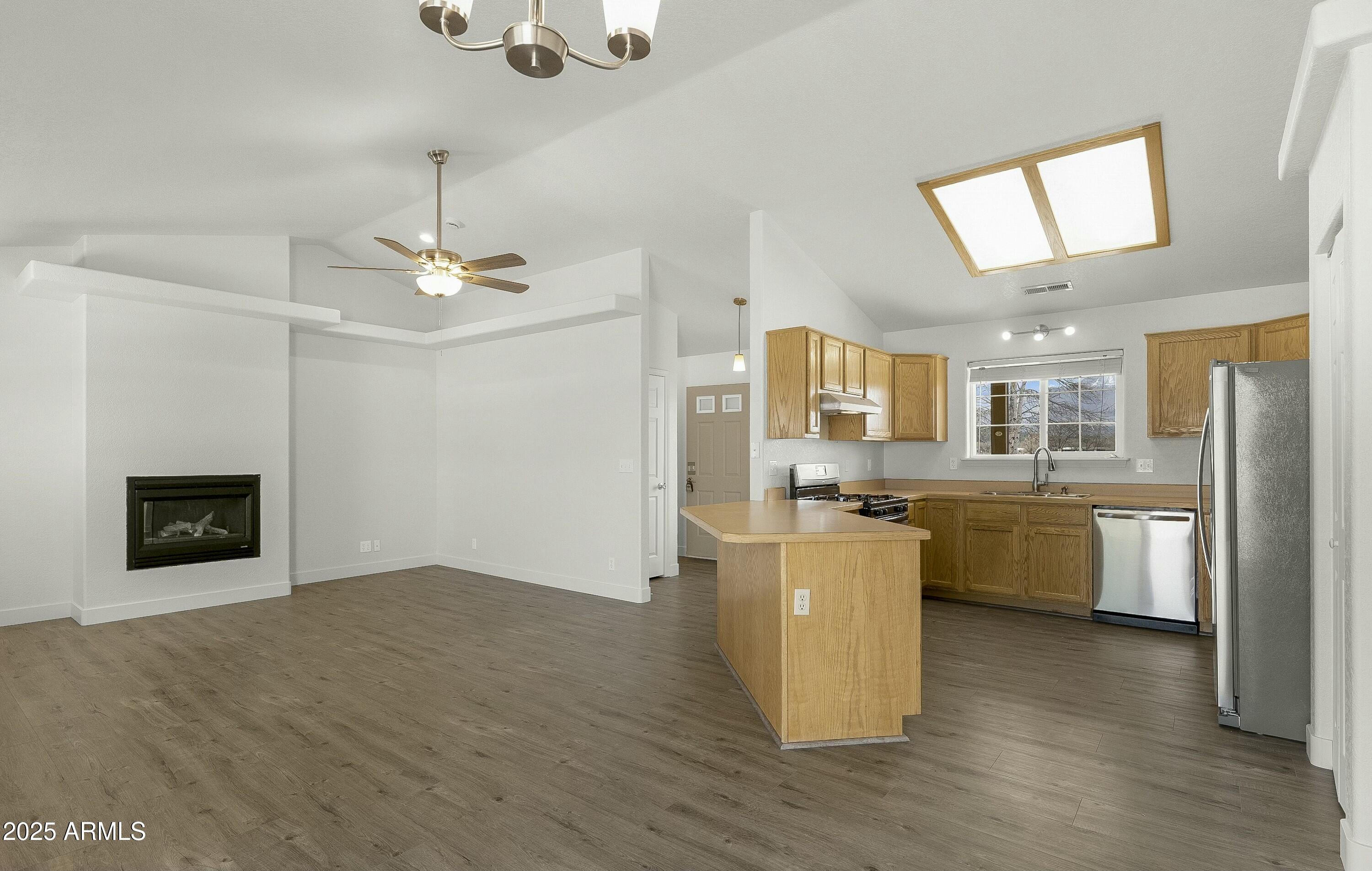 8080 Wendy's Way Flagstaff, AZ 86004 - Photo 4 of 18 a open kitchen with a refrigerator a stove top oven a sink dishwasher and white cabinets with wooden floor