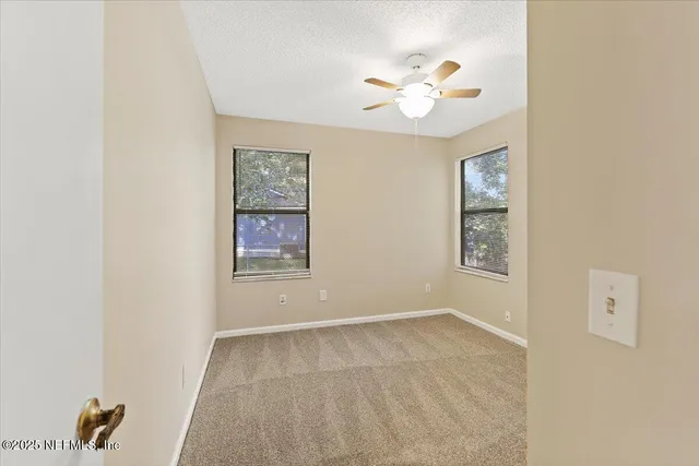 a view of an empty room with a window and a kitchen view