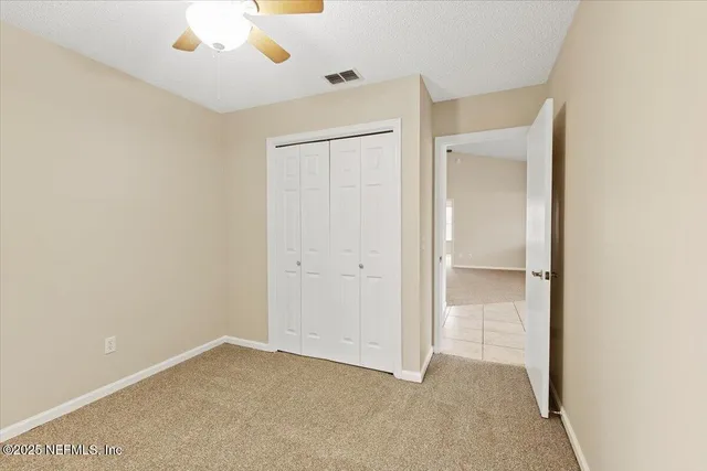 an empty room with windows and fan