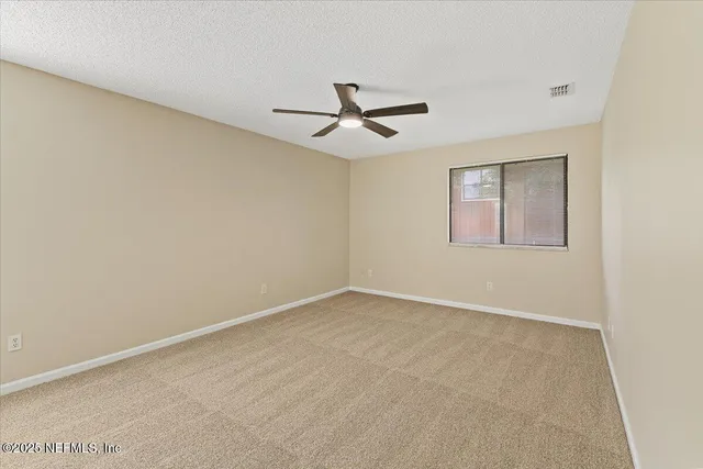 an empty room with a window and ceiling fan