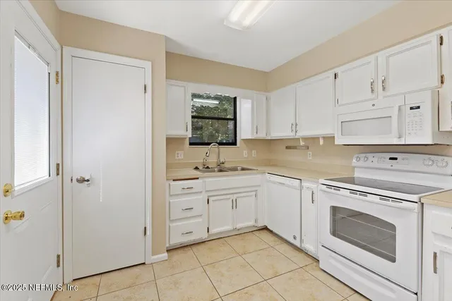 a large white kitchen with a sink a microwave and cabinets