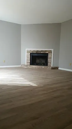 a view of empty room with wooden floor and fireplace