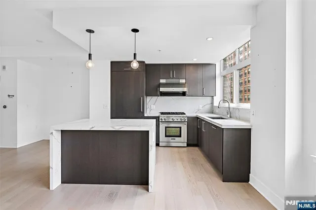 a kitchen with stainless steel appliances kitchen island granite countertop a stove a sink and a refrigerator