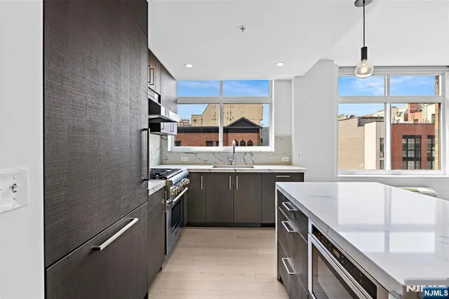 a kitchen with stainless steel appliances granite countertop a sink a stove and a refrigerator