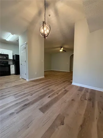 an empty room with wooden floor and kitchen view