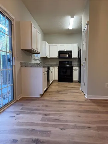 a kitchen with granite countertop a refrigerator and a stove top oven