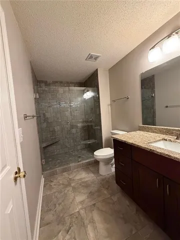 a bathroom with a granite countertop sink toilet and shower