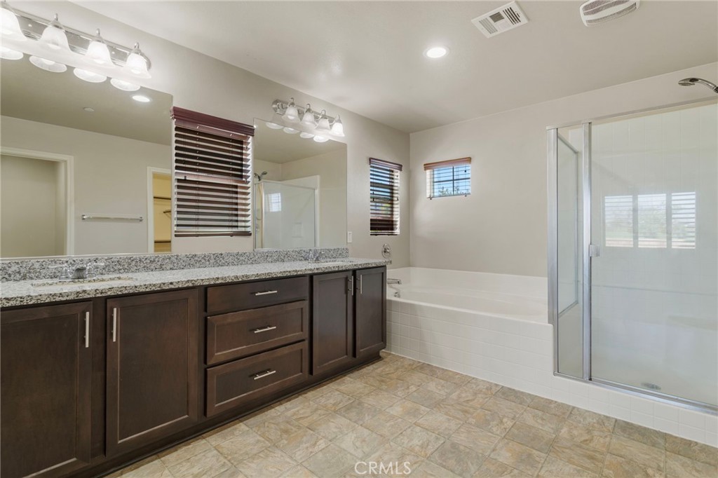 11462 Jacobsen Road Beaumont, CA 92223 - Photo 25 of 45 a bathroom with a granite countertop double vanity sink a mirror and a bathtub