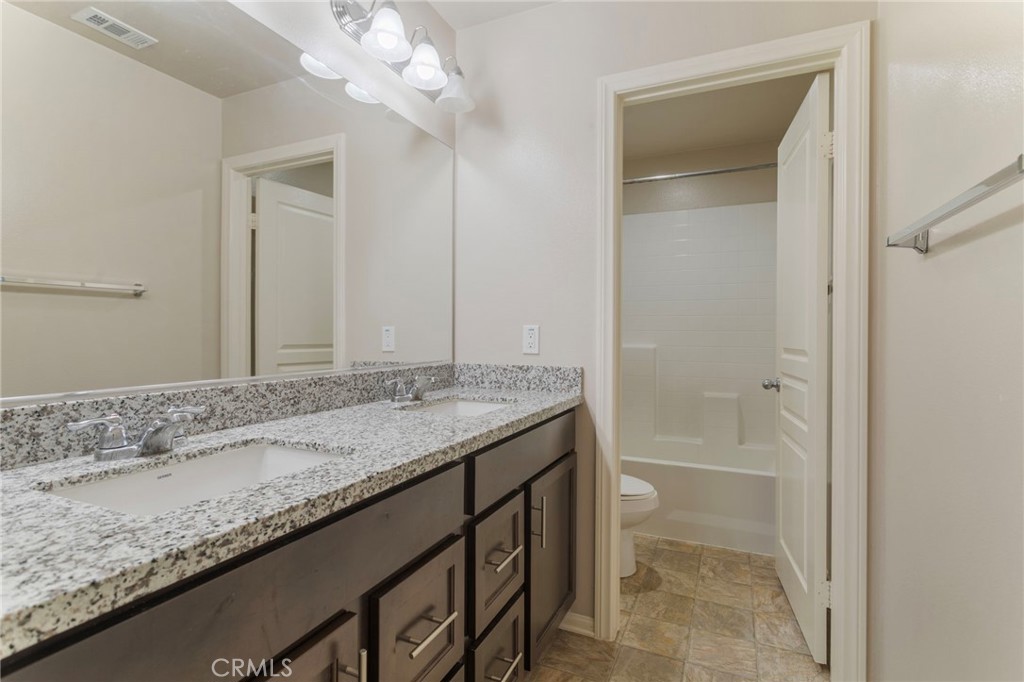 11462 Jacobsen Road Beaumont, CA 92223 - Photo 28 of 45 a bathroom with a granite countertop sink a toilet and a bathtub