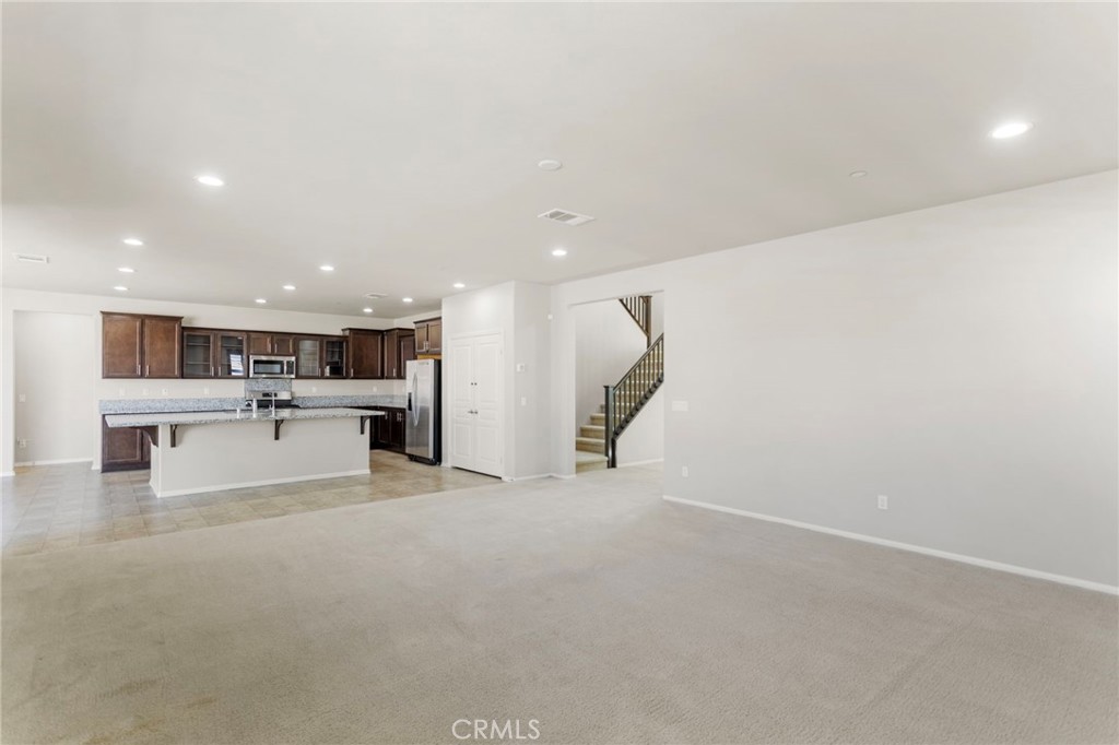 11462 Jacobsen Road Beaumont, CA 92223 - Photo 7 of 45 a view of a kitchen with kitchen island a sink a stove and a refrigerator with a large mirror