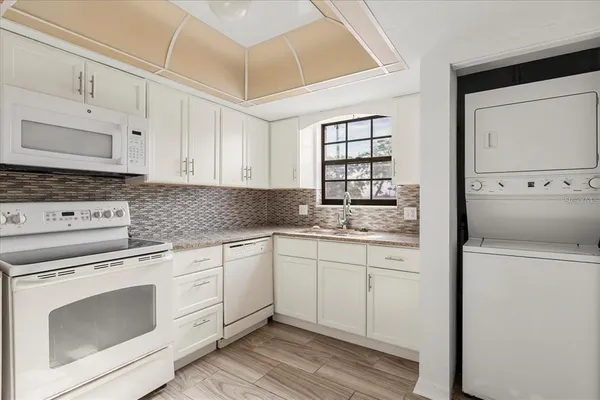 a kitchen with granite countertop white cabinets and white appliances