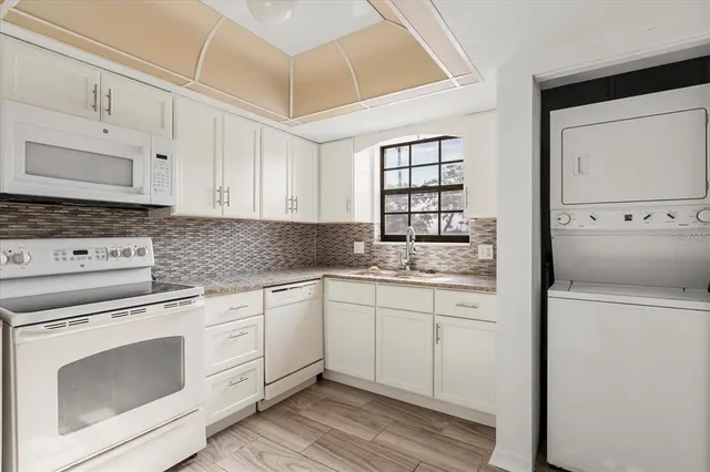 a kitchen with granite countertop white cabinets and white appliances