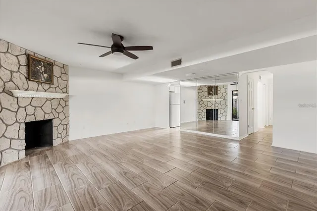 an empty room with wooden floor fireplace and windows
