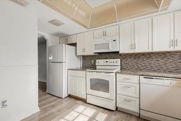 a kitchen with white cabinets and white appliances