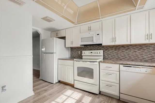 a kitchen with white cabinets and white appliances