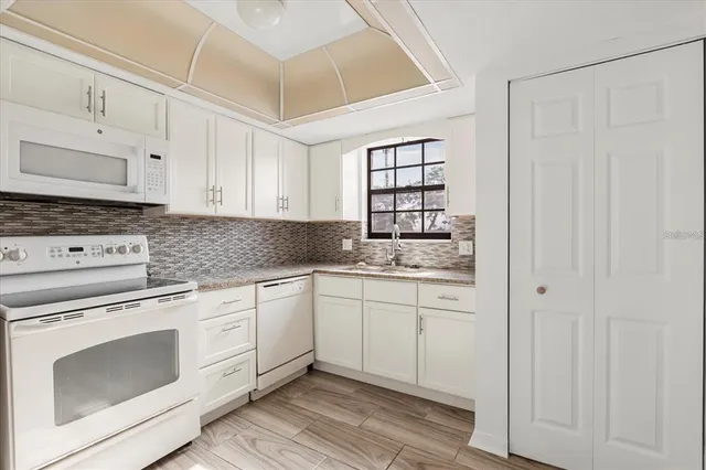 a kitchen with granite countertop white cabinets and white appliances