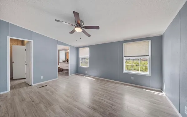 a view of an empty room with a window and wooden floor