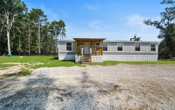 a view of a house with a yard and large tree