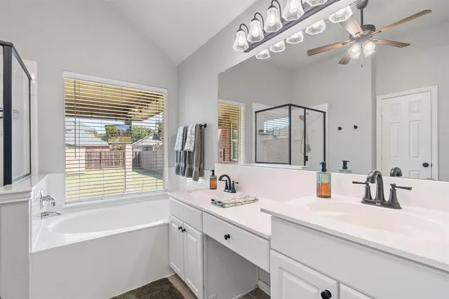 a bathroom with a sink a large mirror and a bathtub next to a window