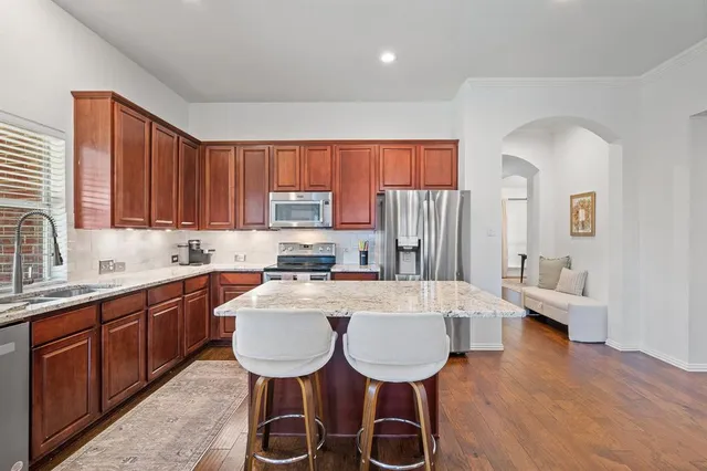 a large kitchen with sink a refrigerator and wooden cabinets