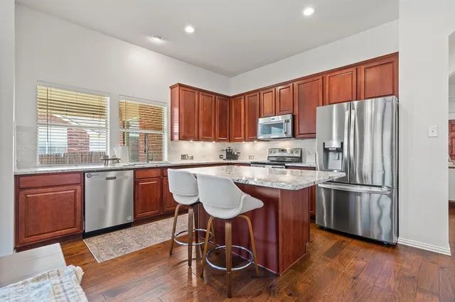 a kitchen with stainless steel appliances granite countertop a stove a sink dishwasher a microwave oven and a refrigerator