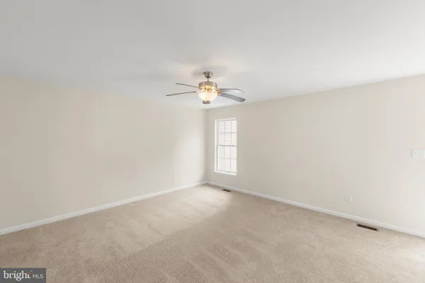 an empty room with a window and a ceiling fan