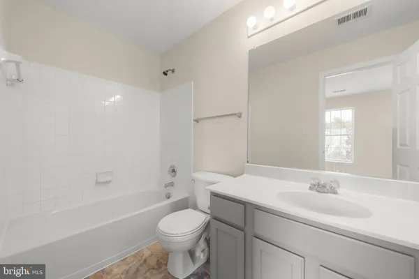 a bathroom with a toilet a sink a mirror a bathtub and vanity