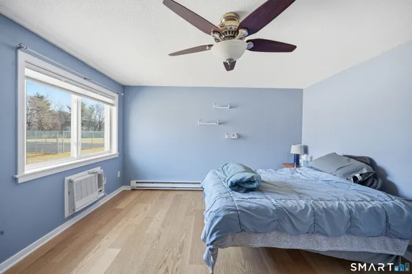 a bedroom with a bed and a large window with wooden floor
