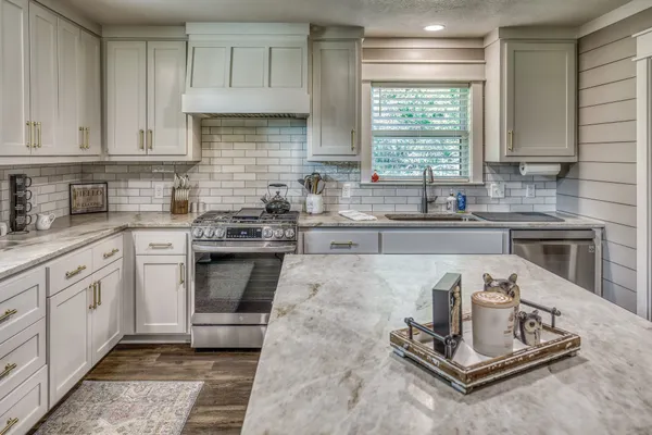 a kitchen with kitchen island granite countertop a sink stove and cabinets