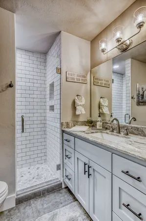 a bathroom with a granite countertop sink a toilet a mirror and shower