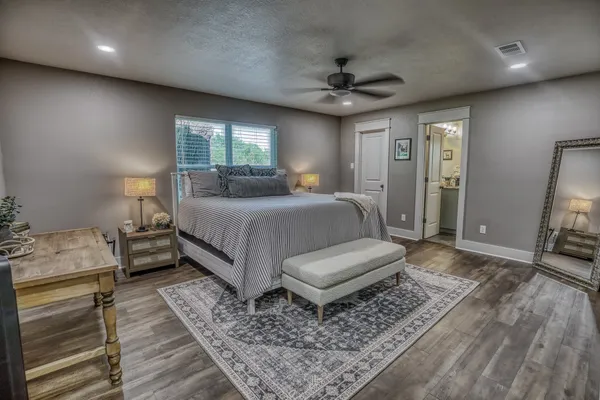 a bedroom with a bed a couches and large mirror with wooden floor