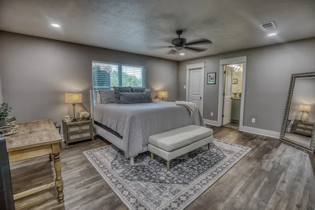 a bedroom with a bed a couches and large mirror with wooden floor