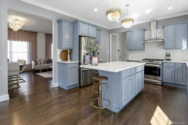 a large kitchen with stainless steel appliances granite countertop a stove and a large countertops with wooden floor