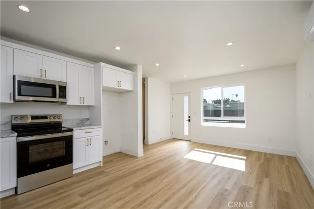 a view of a kitchen with wooden floor and electronic appliances