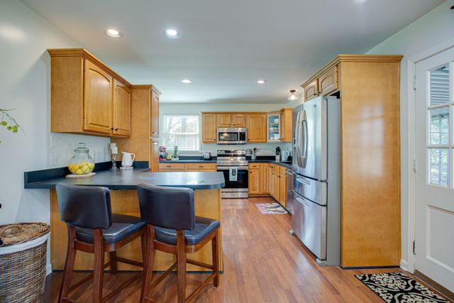 a kitchen with stainless steel appliances granite countertop a refrigerator a sink dishwasher a stove and a refrigerator with wooden floor